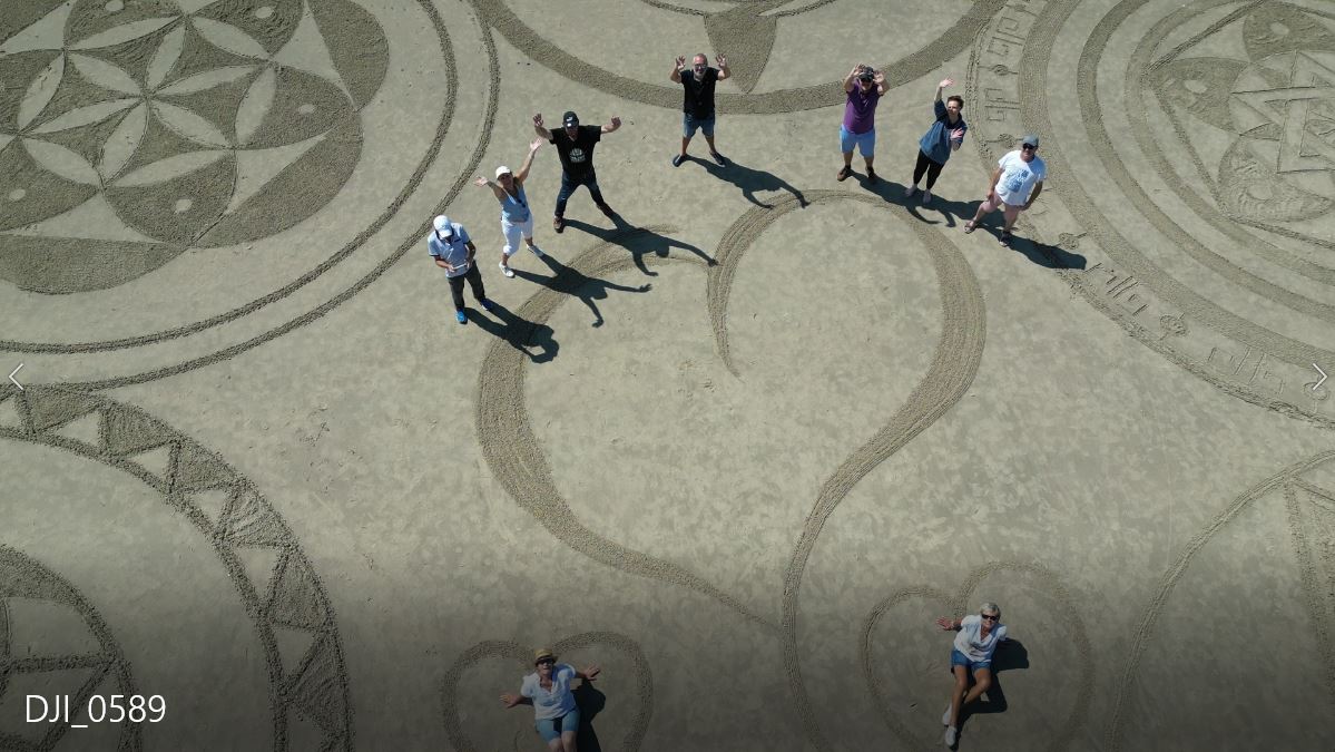 Participants autour d’un grand cœur tracé collectivement dans le sable