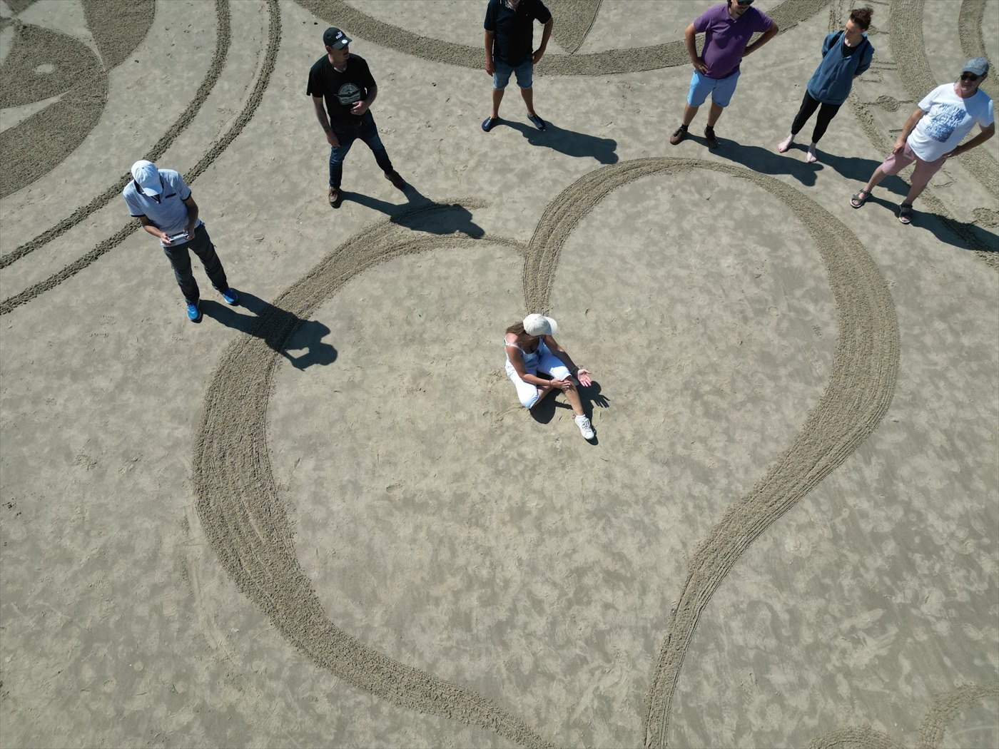 Participants autour d’une création collective en forme de cœur tracée dans le sable