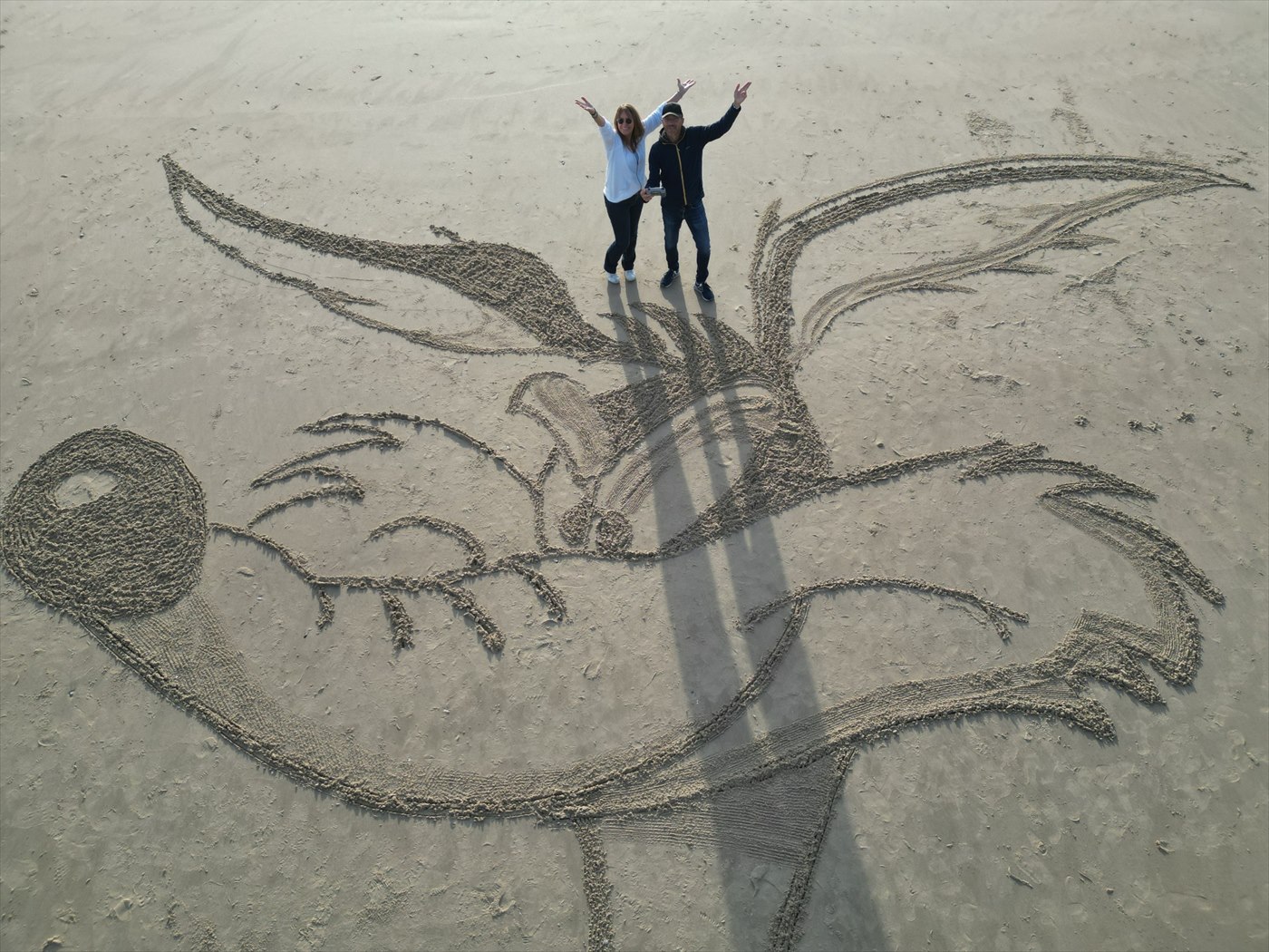 Détail d’une fresque sur le sable avec les créateurs visibles